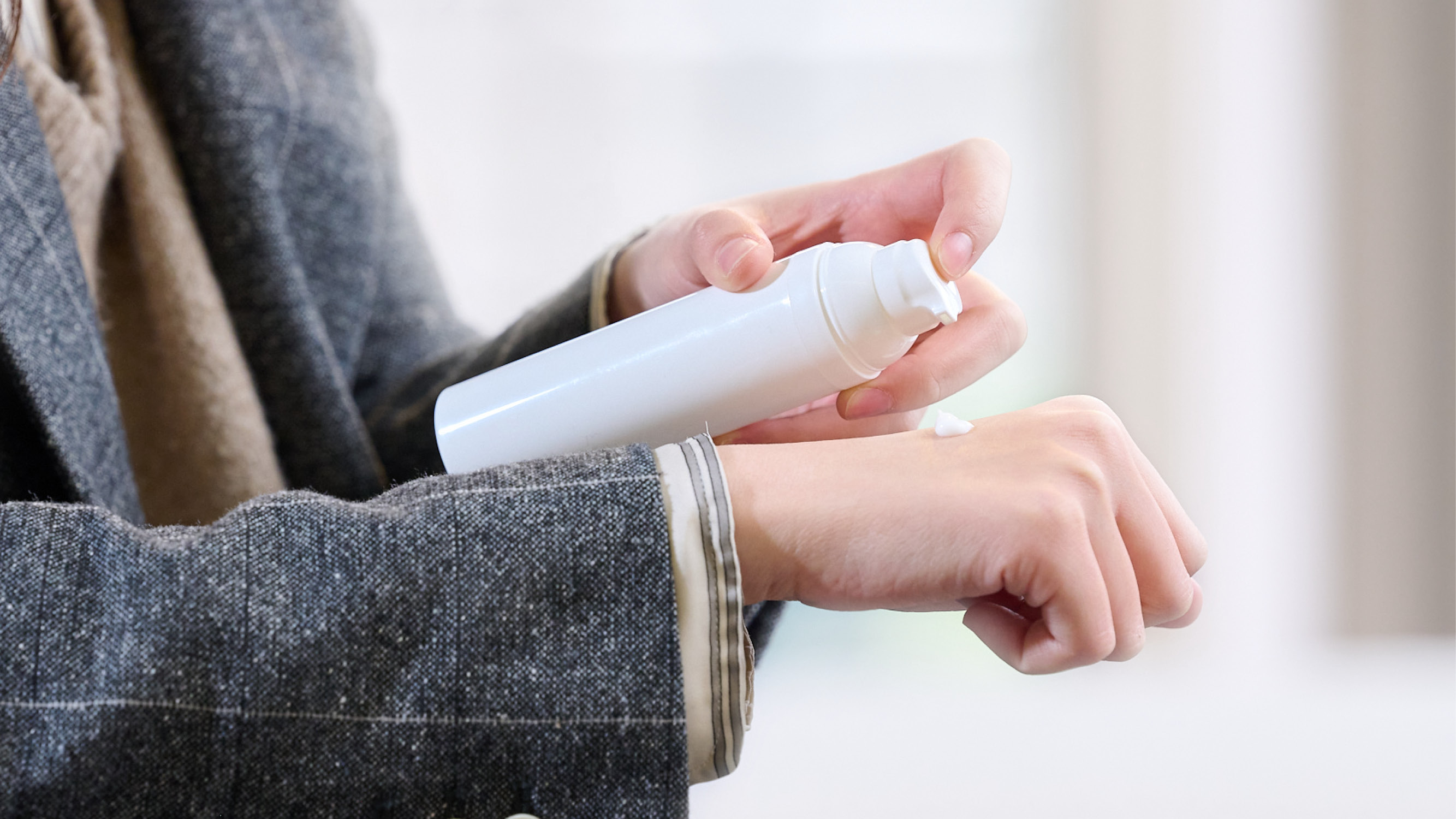 User dispensing a controlled amount of dermal formulation from a metered pump onto the hand for precise application.